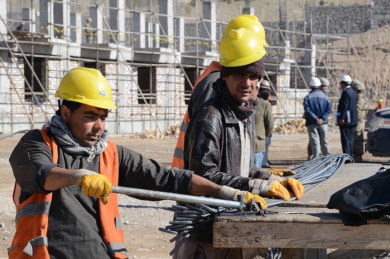 Workers bend reinforcing bar, or rebar, to strengthen concrete for a facility that will house 372 students as part of t…